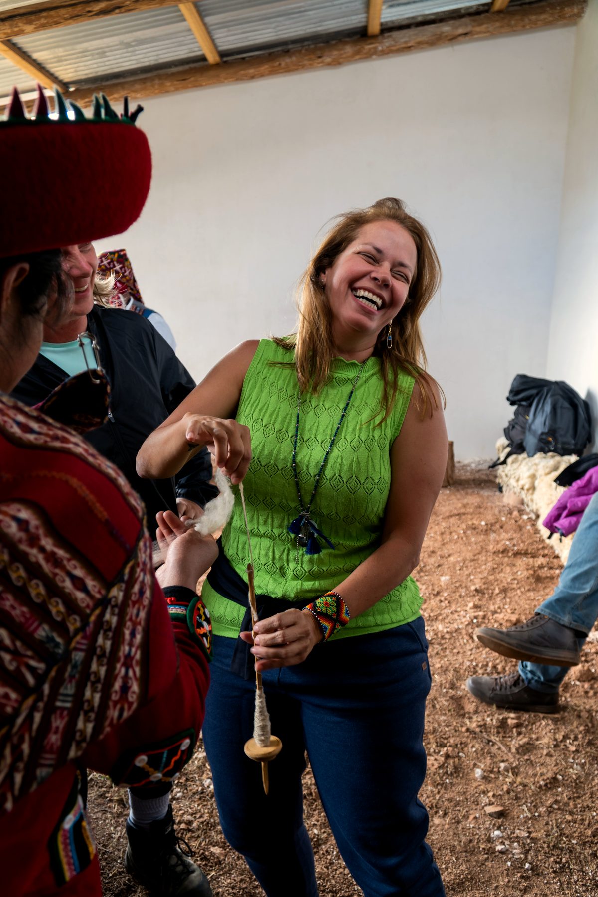 Comunidade andina viva - mulher em chapéu tradicional tecendo com visitante